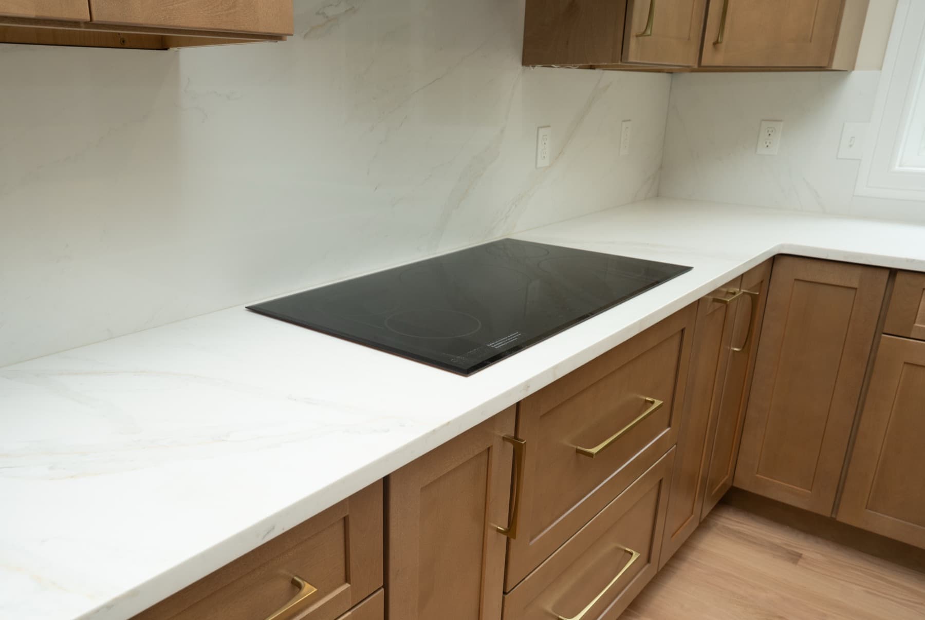 Induction cooktop set into a Calacatta Silverlight countertop with full-height backsplash