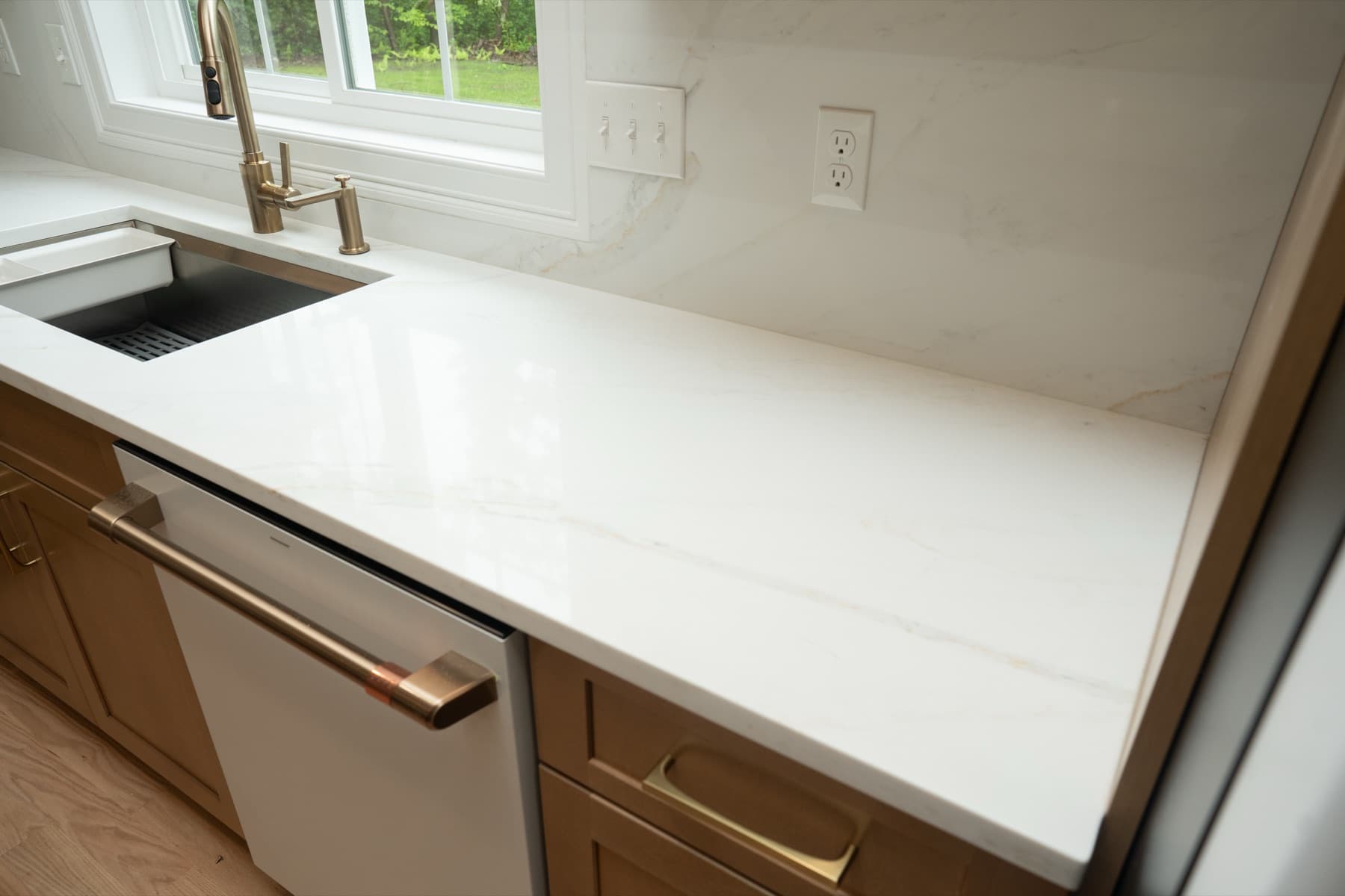 Calacatta Silverlight counter with an undermount sink and brass faucet under a kitchen window