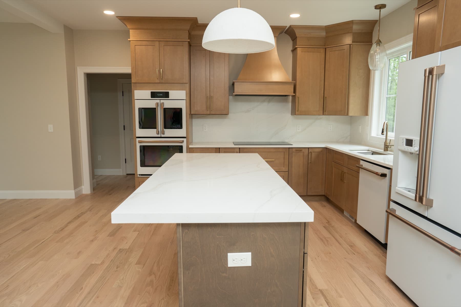 Kitchen with a large Calacatta Silverlight island, matching full-height backsplash, and warm wood cabinetry