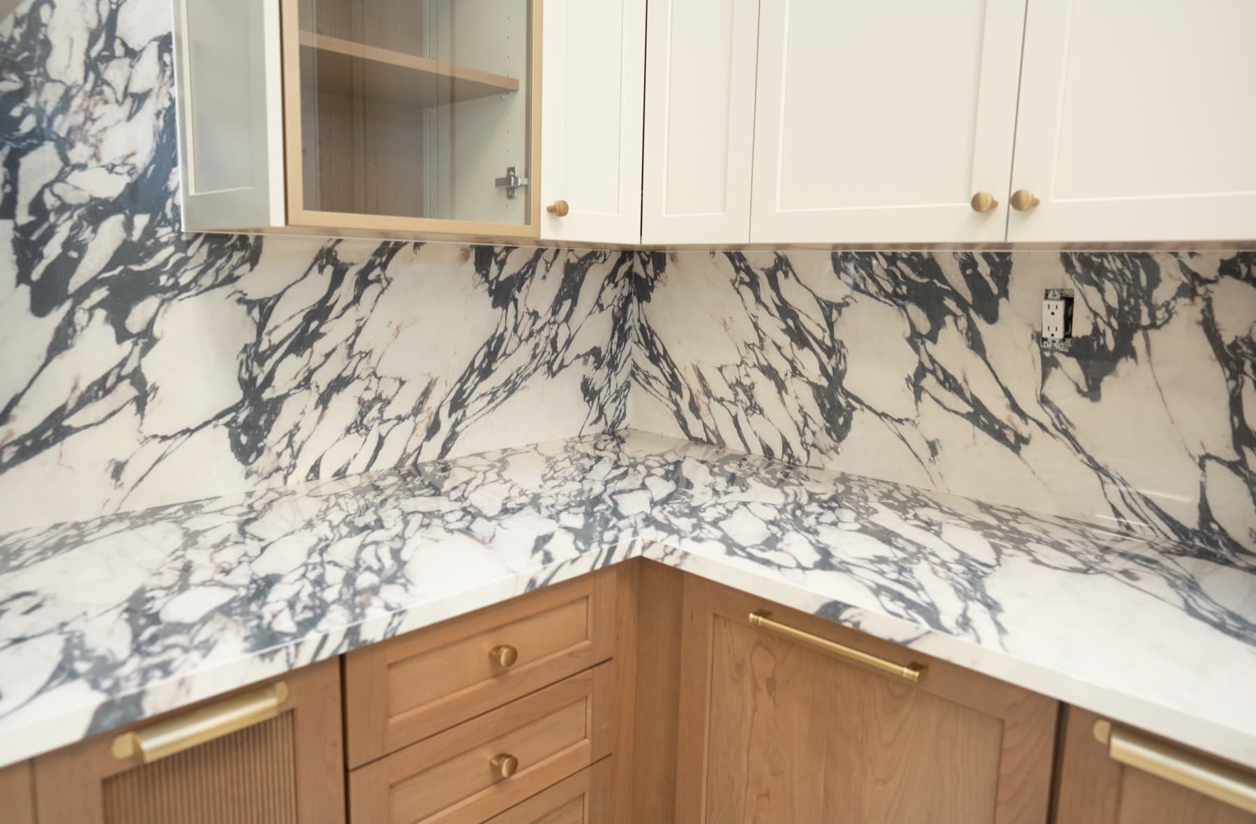 Calacatta Viola porcelain countertop and backsplash with bold violet veining under glass-front cabinets