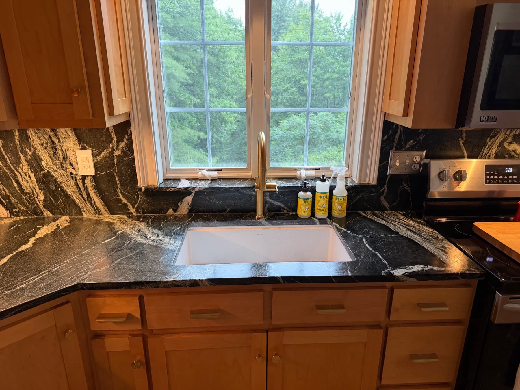 Undermount sink in a dark Grey Venato countertop below a kitchen window