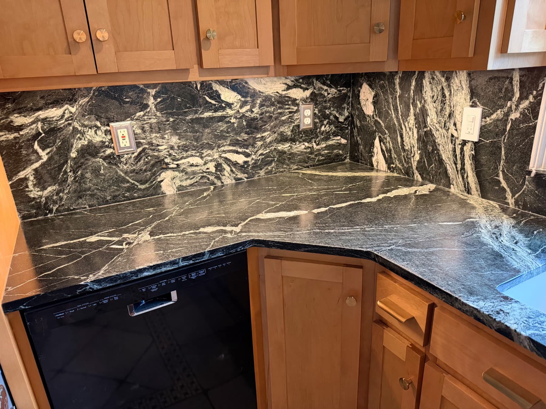 Grey Venato countertop and backsplash corner with white veining over maple cabinets