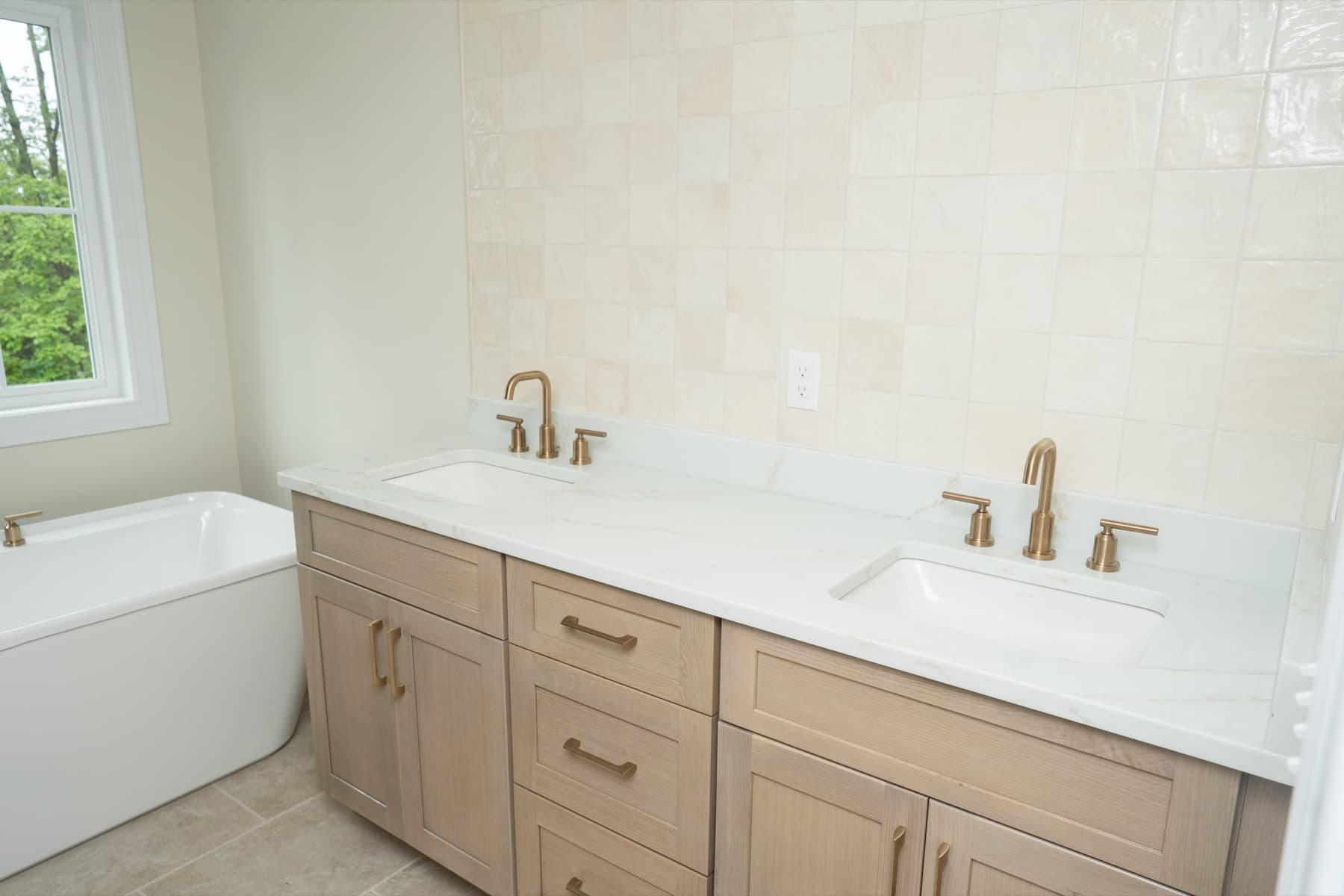 Bathroom with a white oak double vanity, Jasper quartz countertop, brass faucets, and a freestanding tub