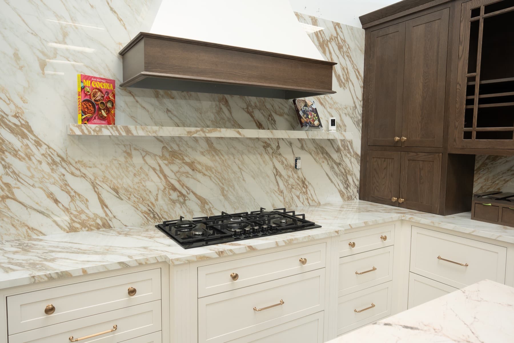 Magellano slab wall behind a gas cooktop with a matching stone floating shelf