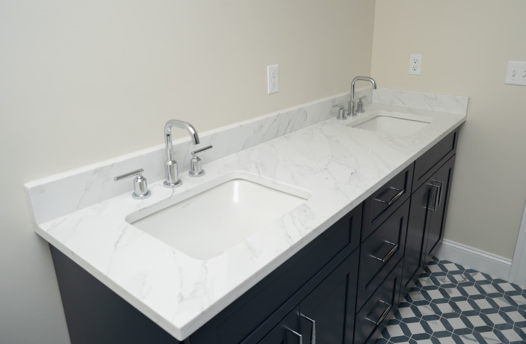 Marfil Grey quartz double vanity top on navy cabinets with a patterned tile floor