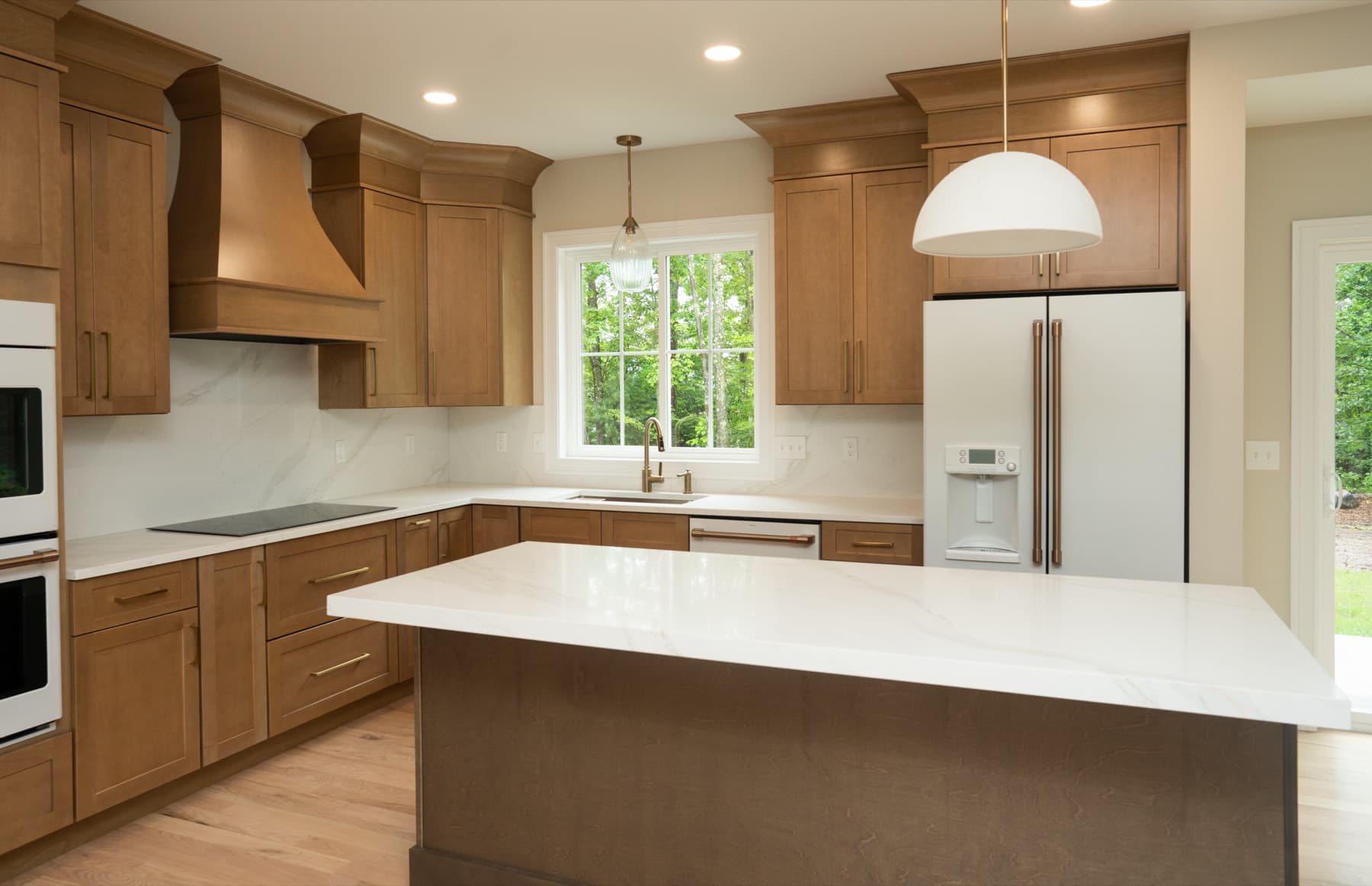 Full kitchen view with Calacatta Silverlight island and counters, wood range hood, and pendant lighting